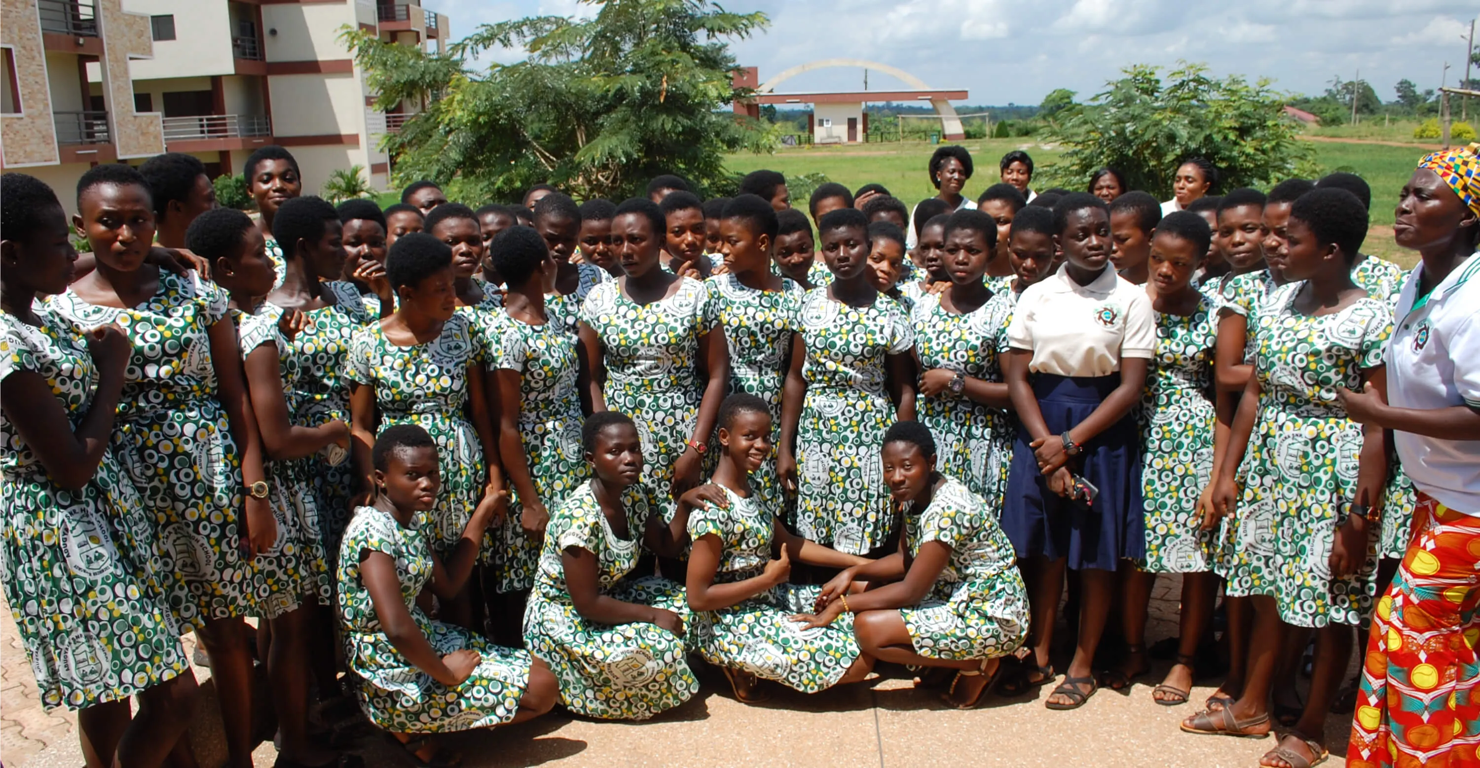 Ministry members in GWEM polo shirts with a large group of senior high school girls in matching print dresses.